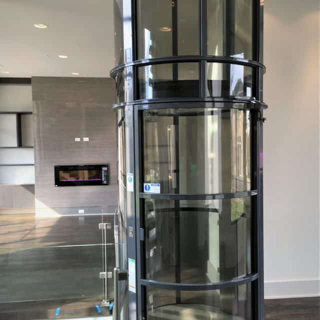 glass elevator with black trim gives a panoramic view during your ride in this houston galleria area residence
