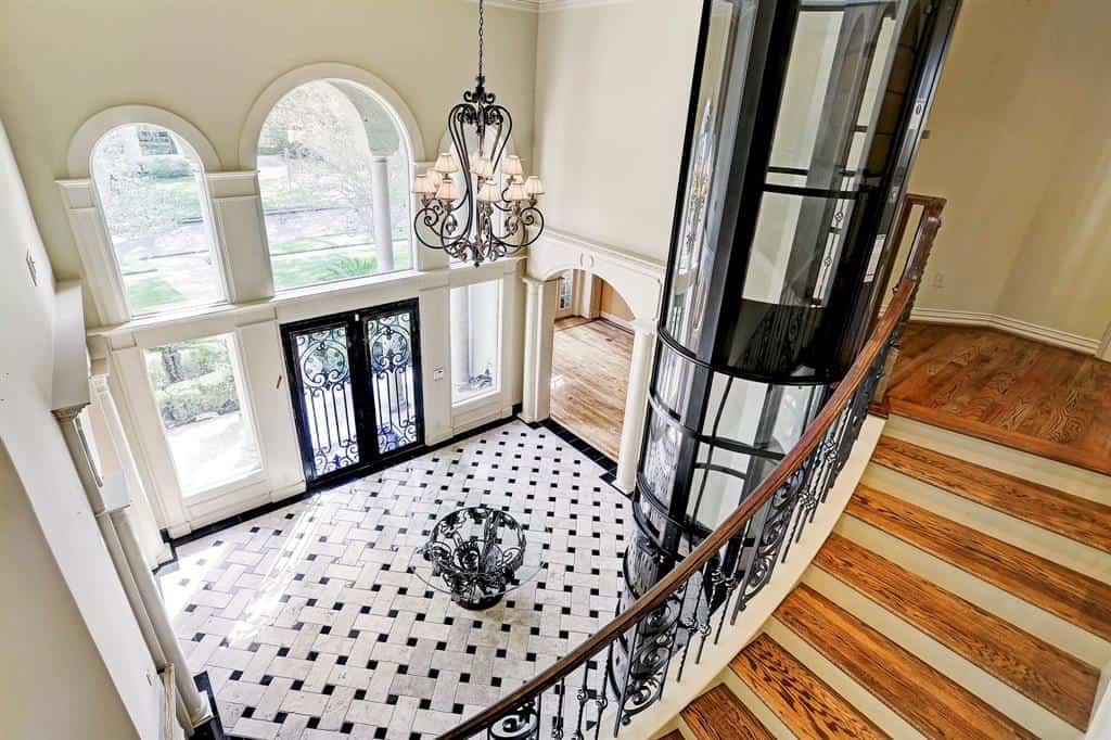 glass PVE elevator installed in the open stairwell of a sweeping staircase of a mediterranean style home