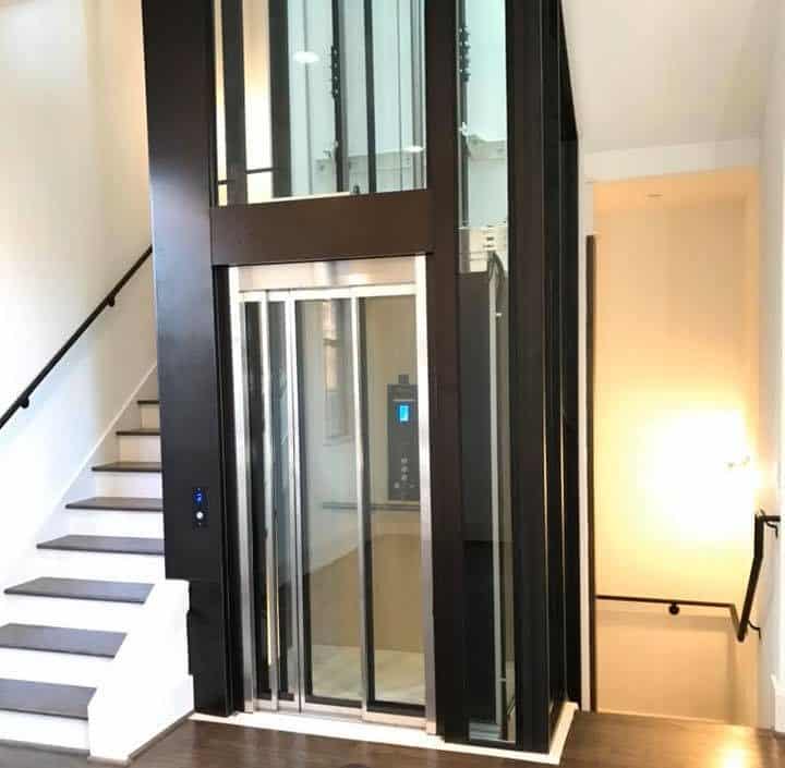 traditional hydraulic elevator in a glass and rich dark wood design